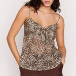 Woman wearing a leopard print top and brown pants on a white background