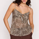 Woman wearing a leopard print top and brown pants on a white background