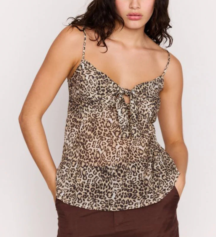Woman wearing a leopard print top and brown pants on a white background