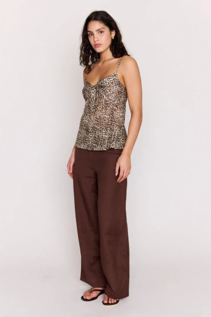 Woman wearing a patterned top and brown pants on a white background
