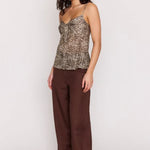 Woman wearing a patterned top and brown pants on a white background