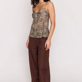Woman wearing a patterned top and brown pants on a white background