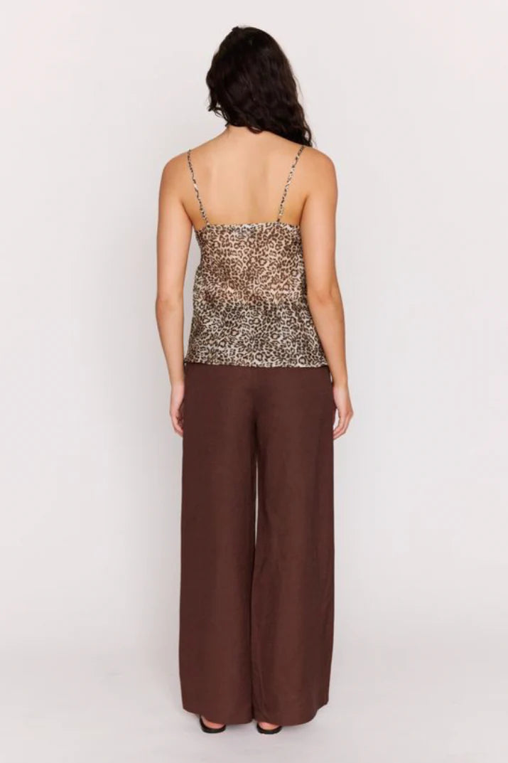 Woman wearing a Leopard print top and brown pants on a white background