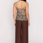 Woman wearing a Leopard print top and brown pants on a white background