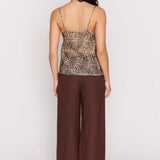 Woman wearing a Leopard print top and brown pants on a white background