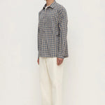 Man wearing a plaid shirt and white pants on a white background