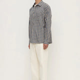 Man wearing a plaid shirt and white pants on a white background