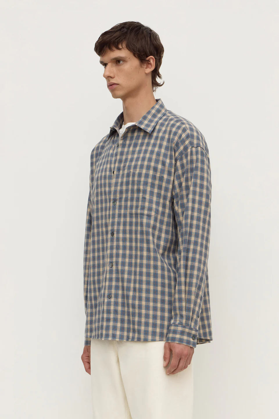 Man wearing a blue and green checkered shirt against a white background