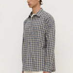 Man wearing a blue and green checkered shirt against a white background