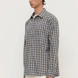 Man wearing a blue and green checkered shirt against a white background