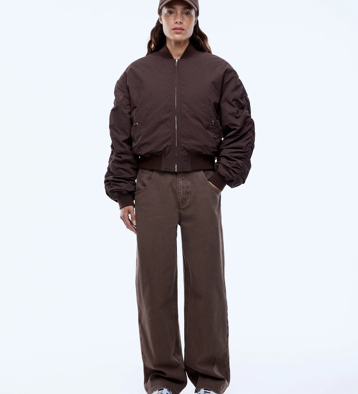 Person wearing a brown jacket and pants with a cap on a white background