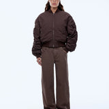 Person wearing a brown jacket and pants with a cap on a white background