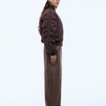 Person wearing a brown outfit with a cap on a white background