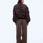 Person wearing a brown jacket and pants with a cap on a white background