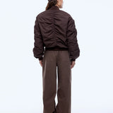 Person wearing a brown jacket and pants with a cap on a white background