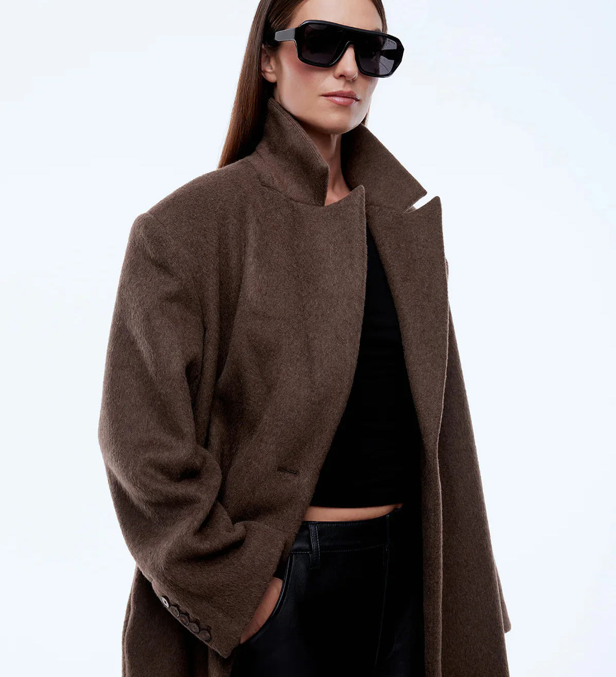 Person wearing a brown coat and sunglasses on a white background