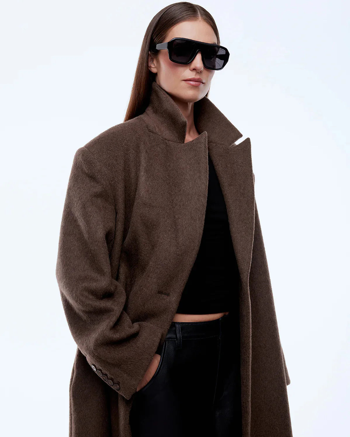 Person wearing a brown coat and sunglasses on a white background