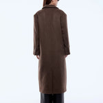 Person wearing a long brown coat on a white background