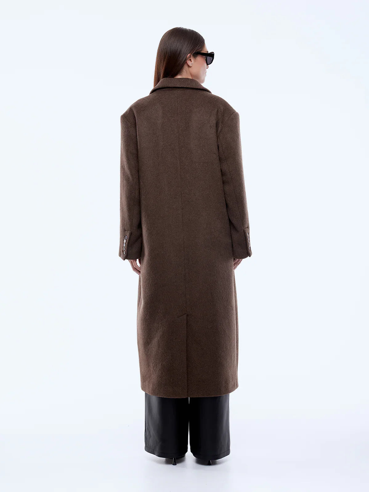 Person wearing a long brown coat on a white background