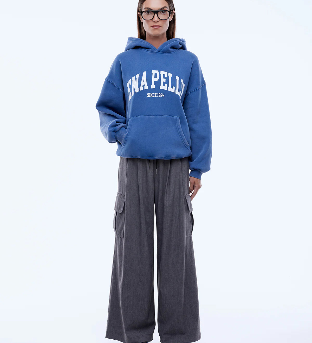 Person wearing a blue hoodie with 'ENAPELLY' branding and gray pants on a white background