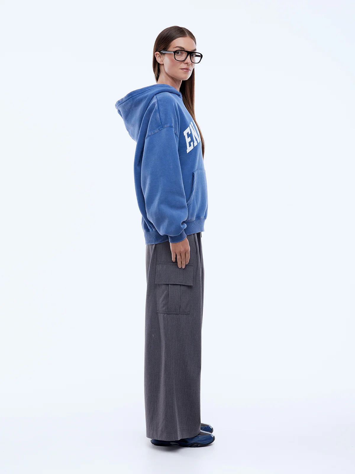 Person wearing a blue hoodie with a logo and gray pants on a white background
