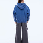 Person wearing a blue hoodie and gray pants on a white background