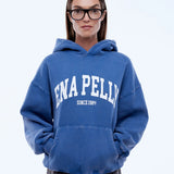 Person wearing a blue hoodie with 'ENA PELLY' branding on a light gray background