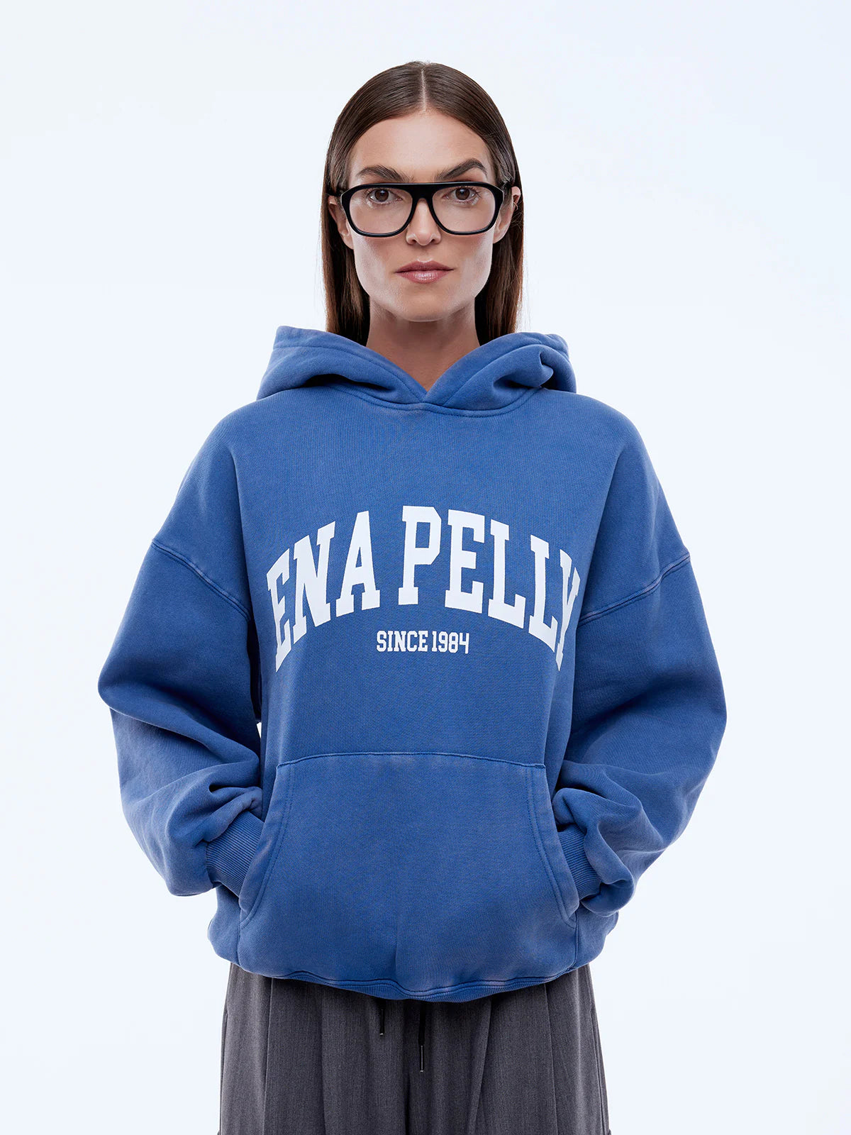 Person wearing a blue hoodie with 'ENA PELLY' branding on a light gray background