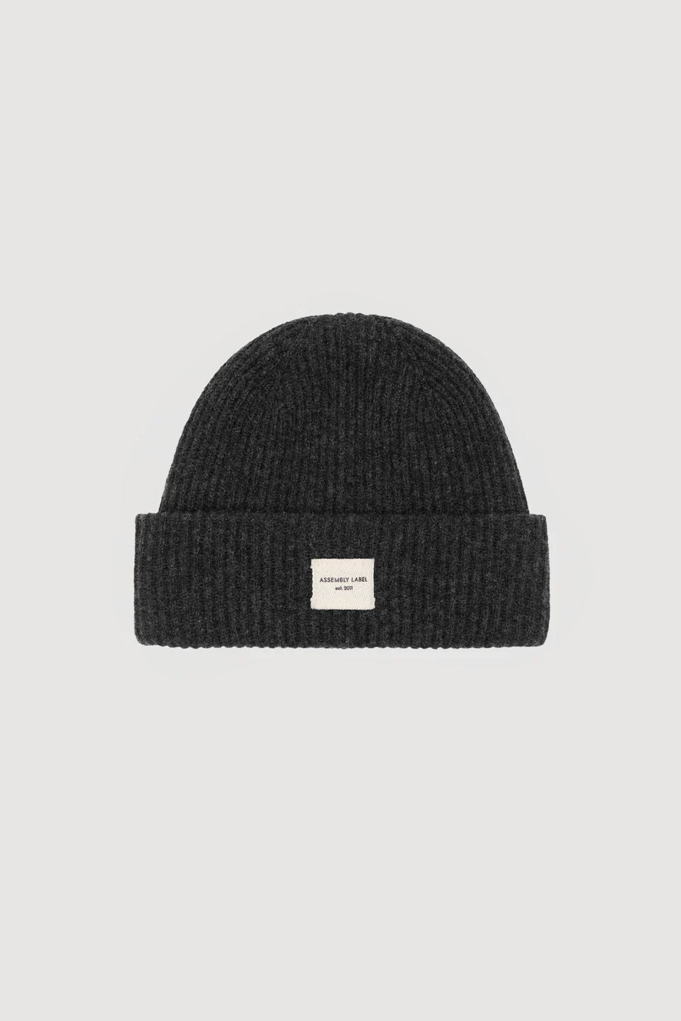 Black knit beanie with a small white label on a light gray background