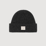 Black knit beanie with a small white label on a light gray background
