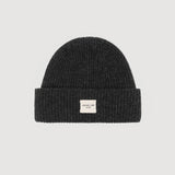 Black knit beanie with a small white label on a light gray background