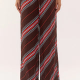 A person wearing loose, wide-leg drawstring pants with diagonal stripes in brown, red, white, and gray, shown from the waist down against a plain light background.
