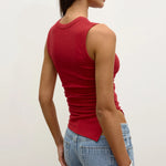Woman wearing a red tank top and blue jeans against a white background