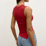 Woman wearing a red tank top and blue jeans against a white background