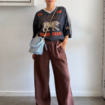 Person wearing a graphic t-shirt and brown pants indoors.