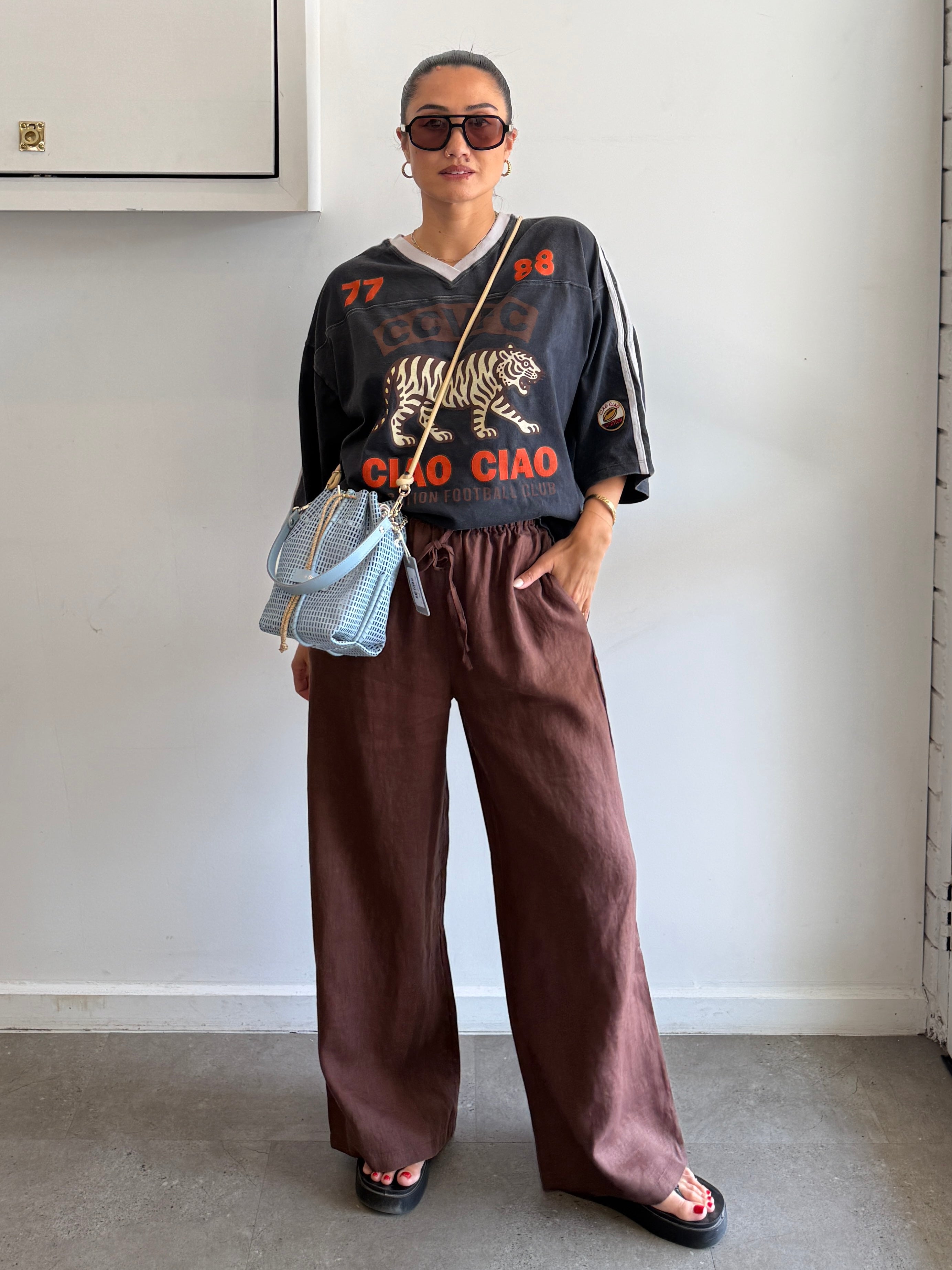 Person wearing a graphic t-shirt and brown pants indoors.