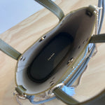 Green handbag with gray tassels and braided handle