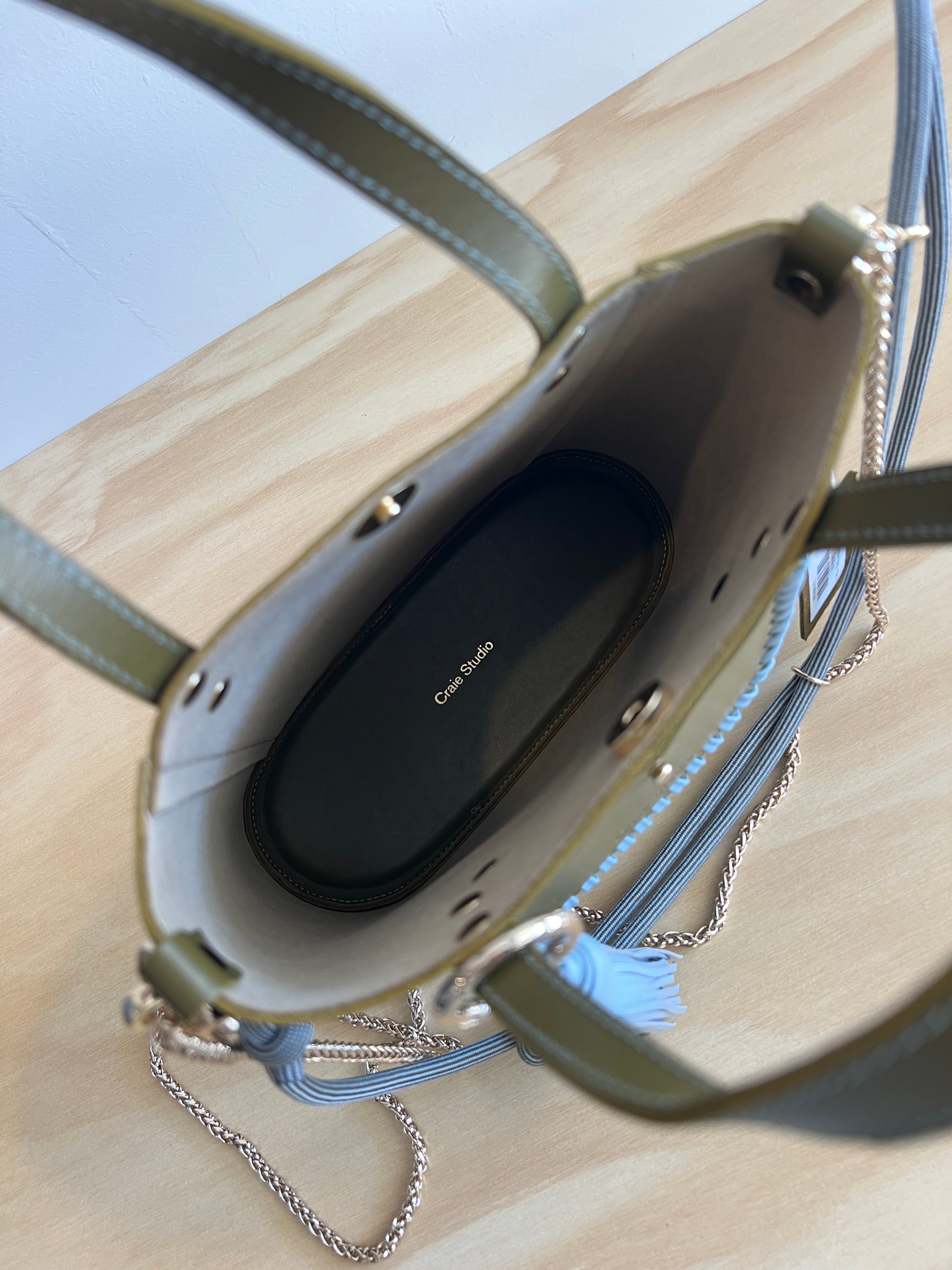 Green handbag with gray tassels and braided handle