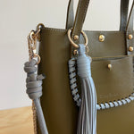 Green handbag with decorative tassels and a visible brand logo.