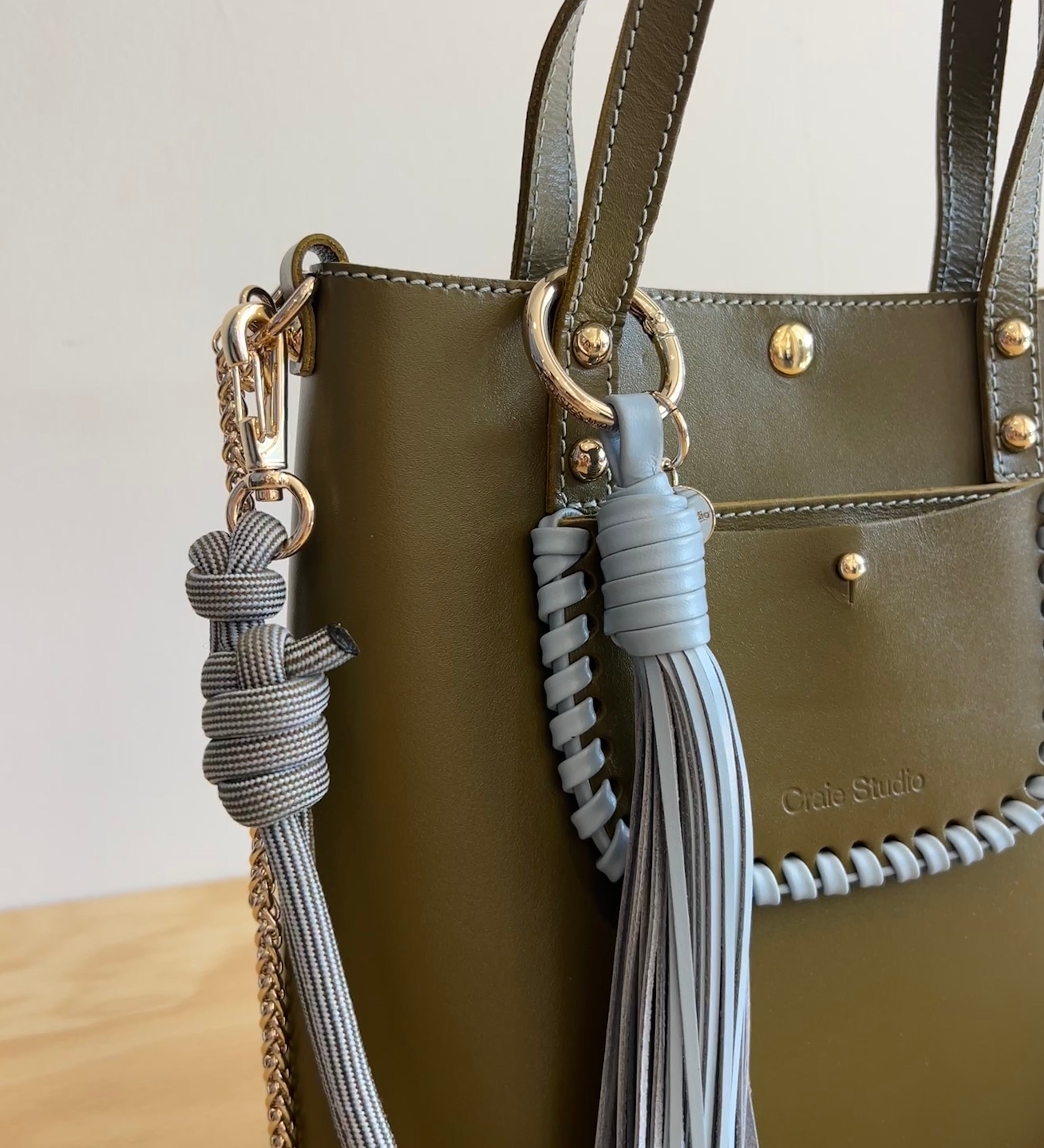 Green handbag with decorative tassels and a visible brand logo.