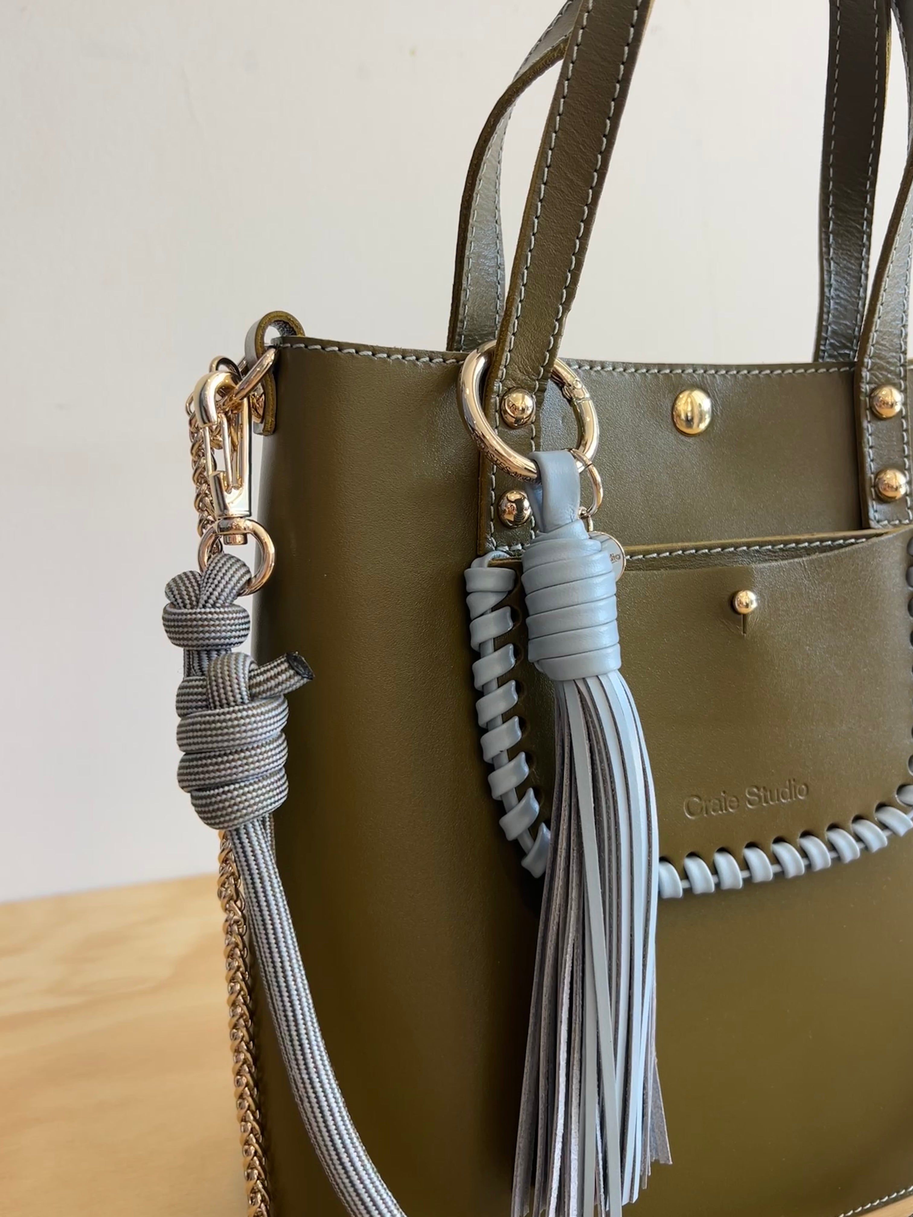 Green handbag with decorative tassels and a visible brand logo.