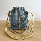 Woven bucket bag with beige handle on a wooden surface