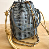 Blue woven drawstring bag with beige shoulder strap on a wooden surface