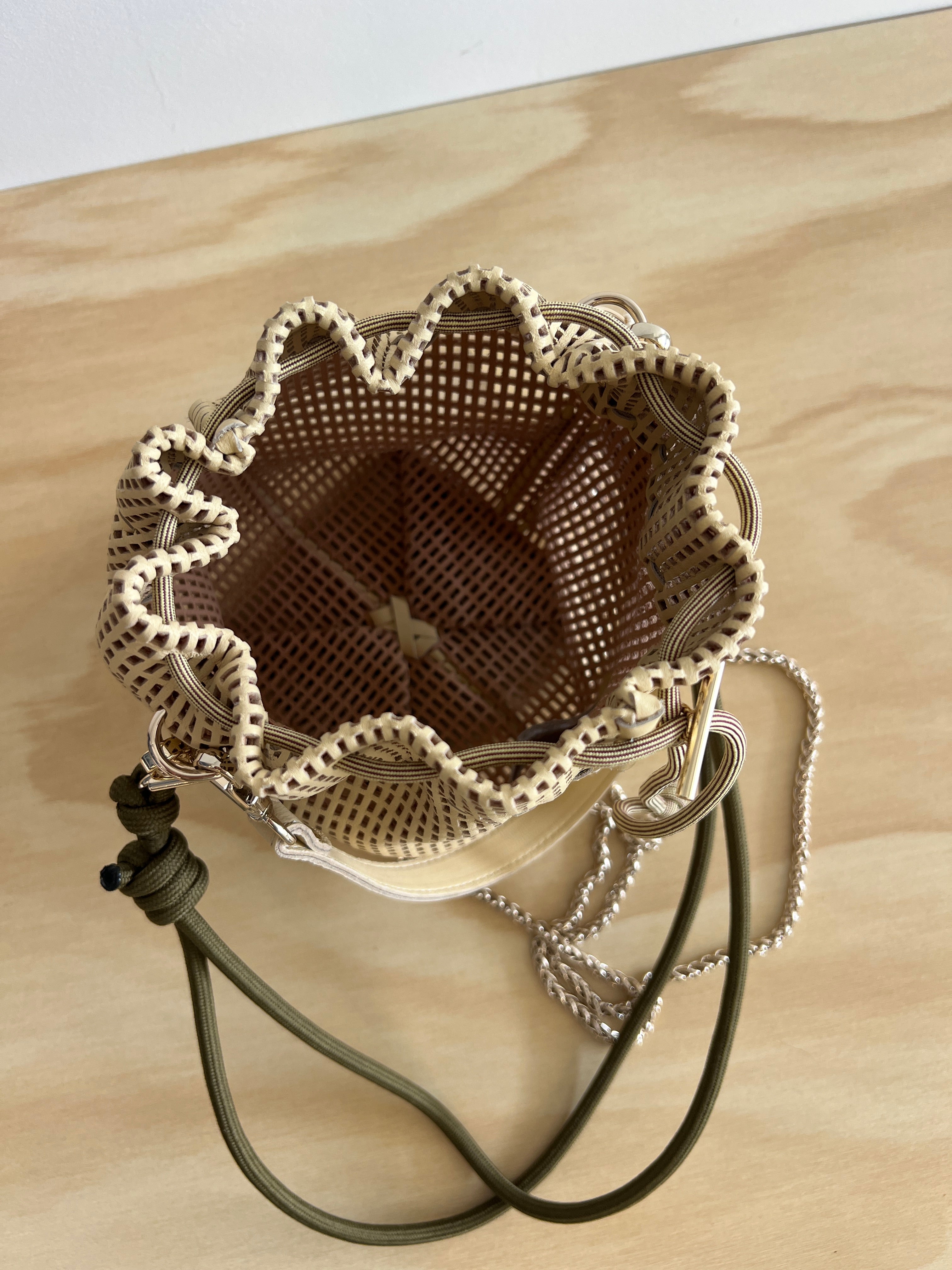 leather bag on a wooden table with a drawstring and chain