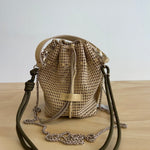 Woven bag with drawstring and leather straps on a wooden surface