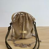 Woven bag with drawstring and leather straps on a wooden surface