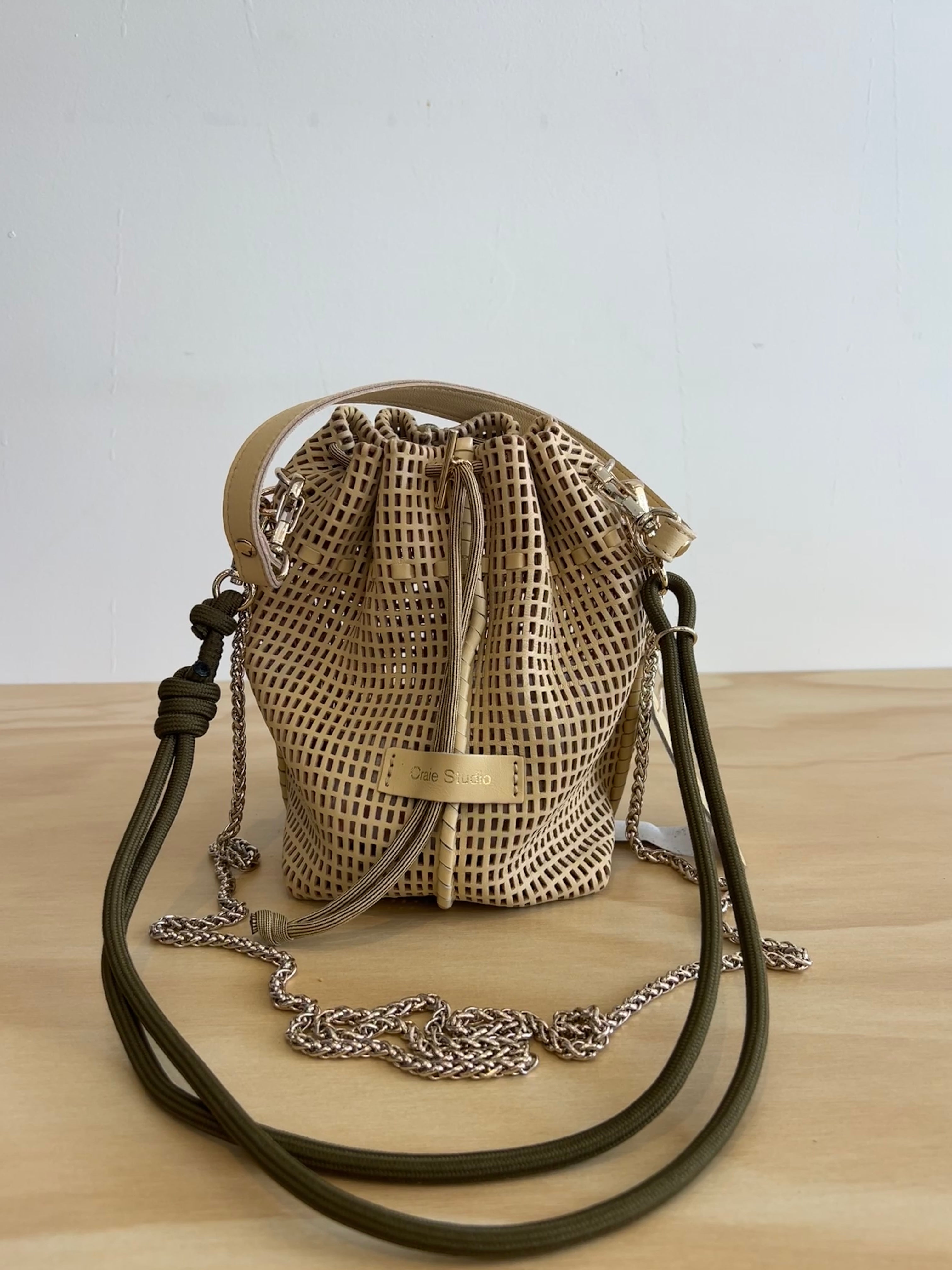 Woven bag with drawstring and leather straps on a wooden surface