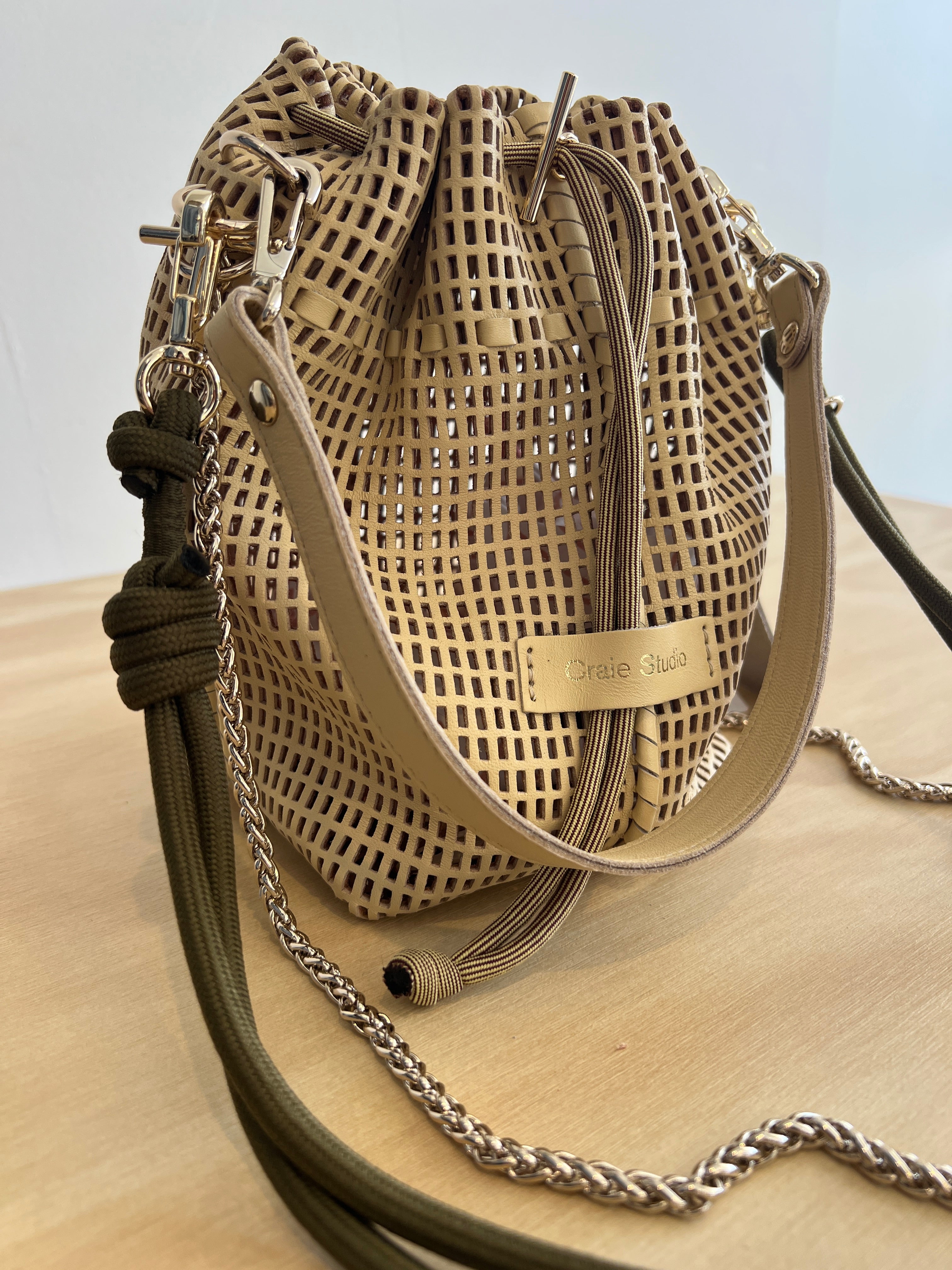 Woven handbag with chain detail on a neutral background