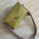 Mustard leather cross body bag in a wooden surface