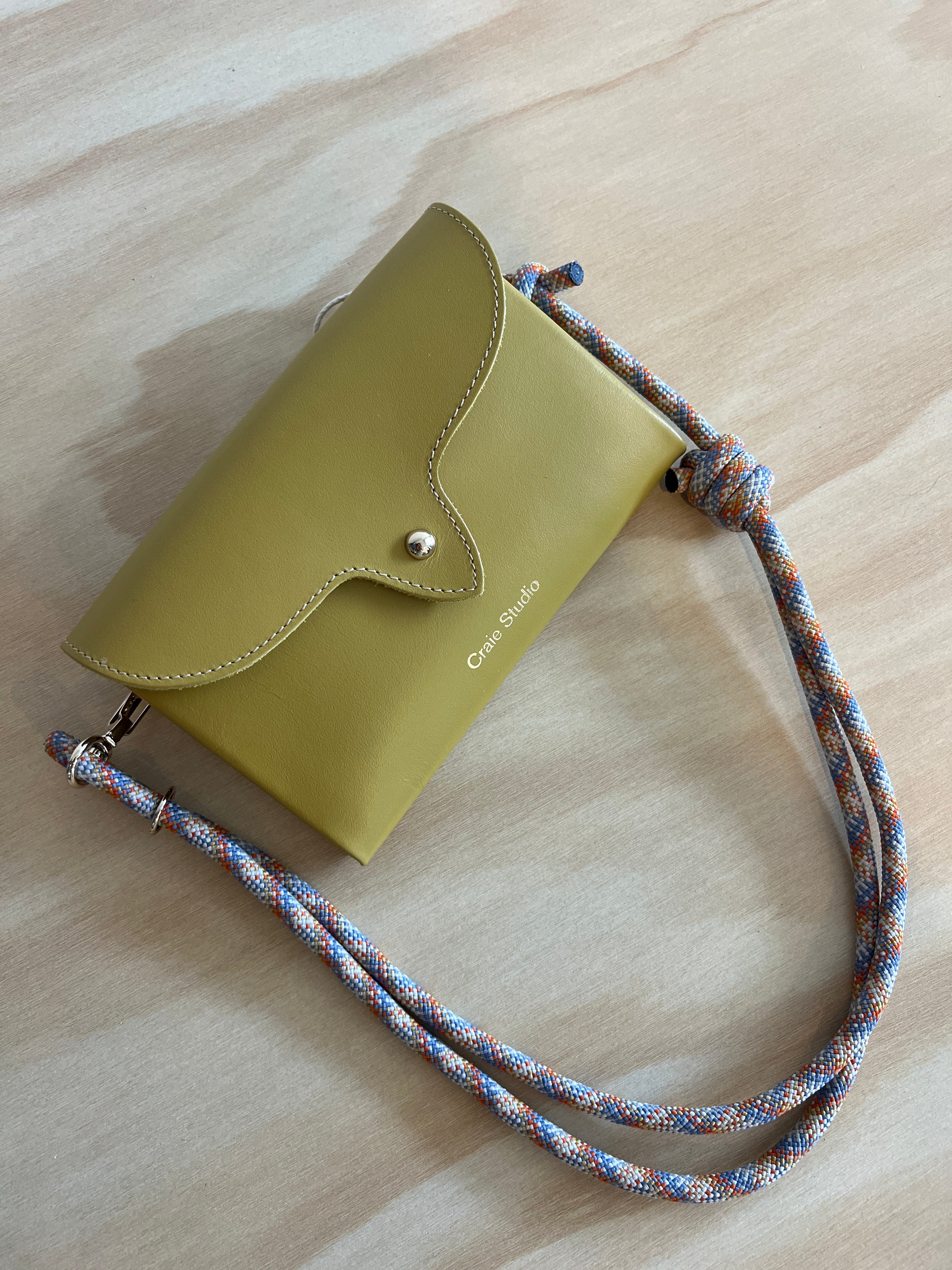 Mustard leather cross body bag in a wooden surface